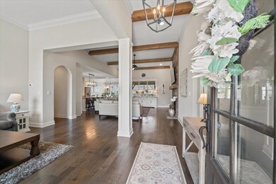 Foyer with a chandelier, hardwood / wood-style flooring, arched walkways, ornate columns, and beamed ceiling