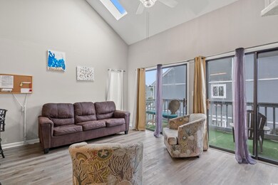 Living area featuring ceiling fan, high vaulted ceiling, a skylight, wood finished floors, and baseboards