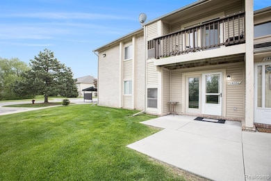 Rear view of house with a balcony, a patio, a lawn, and brick siding