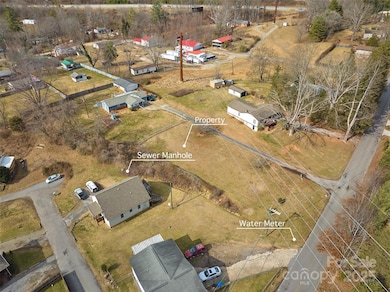 View of lot with Moody Ave along right side of photo.  Water meter located at street.  4 locations nearby provide access to public sewer but will require private easements to obtain