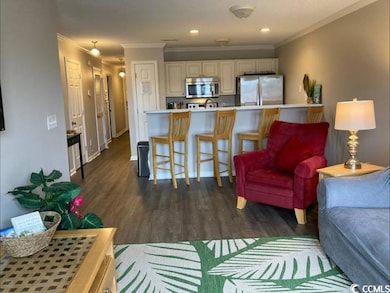 Living area with ornamental molding, dark wood finished floors, and recessed lighting