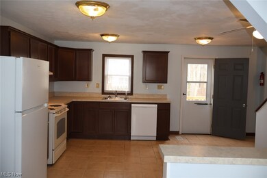 Kitchen featuring dark brown cabinetry, white appliances, sink, light tile floors, and ceiling fan