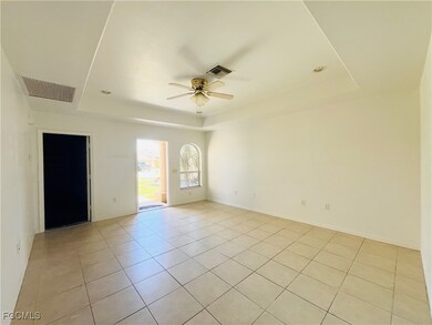 Unfurnished room with a raised ceiling, light tile patterned flooring, and ceiling fan