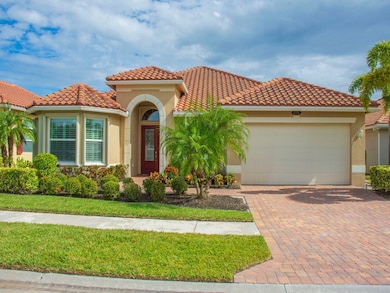 Mediterranean / spanish home featuring stucco siding, decorative driveway, an attached garage, a tile roof, and a front lawn