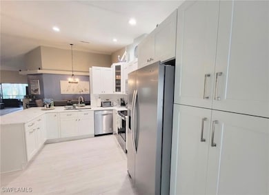 Kitchen featuring stainless steel appliances, a peninsula, white cabinets, glass insert cabinets, and open floor plan