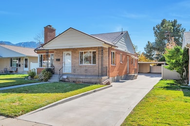 Bungalow featuring a front yard, a porch, a chimney, concrete driveway, and a mountain view
