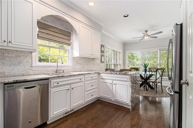 Kitchen with stainless steel appliances, dark wood-style flooring, a ceiling fan, plenty of natural light, and crown molding