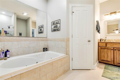 Bathroom featuring a tub with jets, vanity, and ti