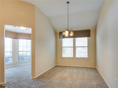 Empty room with vaulted ceiling, carpet floors, a chandelier, and a ceiling fan