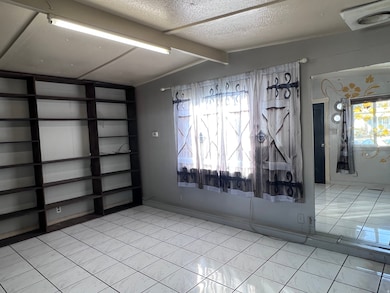 Living room with light tile-patterned floors and a textured ceiling