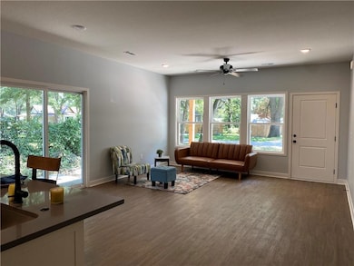 Living room featuring dark wood-style flooring, a ceiling fan, and recessed lighting