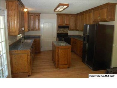 Kitchen has hardwood floors, plenty of cabinet space, and tile countertops.