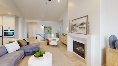 Living area featuring light wood finished floors, a glass covered fireplace, recessed lighting, a ceiling fan, and high vaulted ceiling