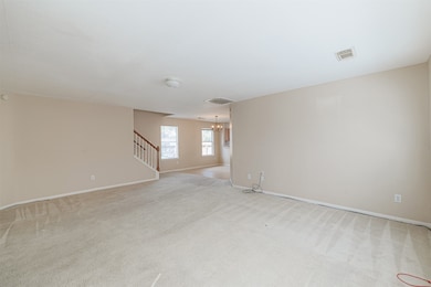 Spacious living room with neutral tones and direct flow into dining and kitchen areas.