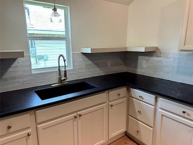 Kitchen with a sink, dark countertops, and decorative backsplash