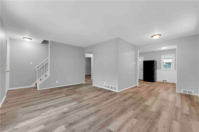 Unfurnished living room featuring light wood-type flooring, visible vents, and stairs