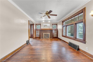 Unfurnished living room featuring dark hardwood / wood-style floors, ceiling fan, a fireplace, and crown molding