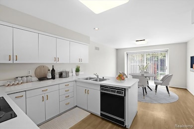 Kitchen featuring a peninsula, black appliances, light wood finished floors, and recessed lighting