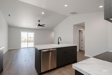 Kitchen with dishwasher, vaulted ceiling, light wood finished floors, a center island with sink, and open floor plan