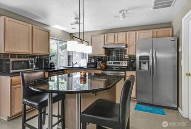 Kitchen features maple cabinets, Black Opal granite countertops, overhead fans, tile backsplash and stylish light fixture. Garden window overlooks side yard area.