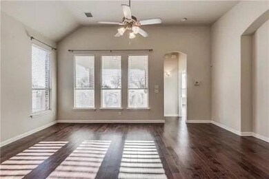 Empty room featuring a healthy amount of sunlight, dark wood-type flooring, ceiling fan, and vaulted ceiling
