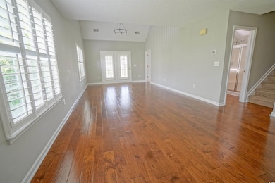 Unfurnished room with wood-type flooring, baseboards, vaulted ceiling, and stairs