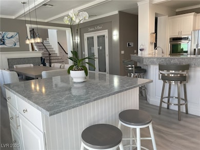 Kitchen with a breakfast bar, white cabinetry, beam ceiling, stainless steel appliances, and light wood-style floors