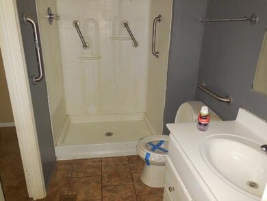 Bathroom featuring tiled shower, vanity, toilet, a