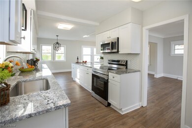  floors, sink, appliances with stainless steel finishes, tasteful backsplash, and white cabinetry