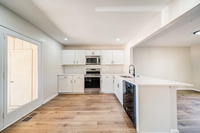 Kitchen featuring white cabinetry, sink, stainless