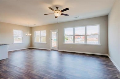 Unfurnished living room featuring dark wood-style flooring, a ceiling fan, and a chandelier
