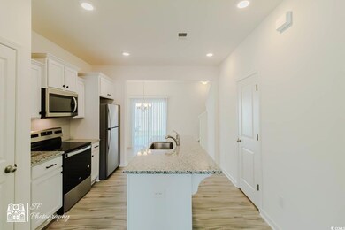 Kitchen featuring appliances with stainless steel finishes, white cabinetry, light wood-style flooring, a chandelier, and recessed lighting