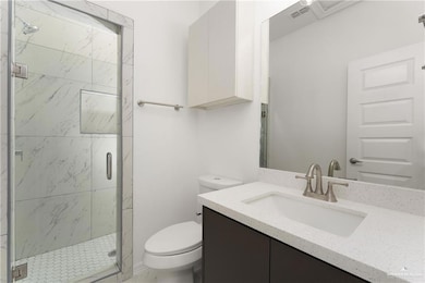 Bathroom featuring vanity, toilet, and a shower with door