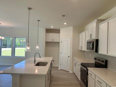 Kitchen featuring appliances with stainless steel finishes, a sink, tasteful backsplash, light wood-style floors, and white cabinetry
