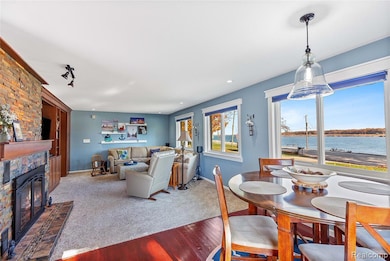 Carpeted living area featuring a water view, wood finished floors, and a large natural fireplace