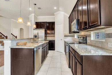 Kitchen with appliances with stainless steel finishes, light stone countertops, decorative light fixtures, light tile patterned floors, and dark brown cabinetry