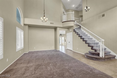 Carpeted foyer with a chandelier, a high ceiling,