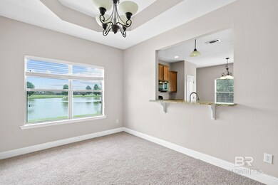 Spare room with a notable chandelier, a tray ceiling, a water view, sink, and carpet floors
