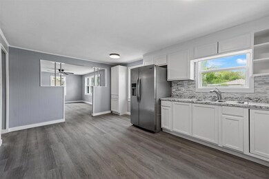 Kitchen with a healthy amount of sunlight, stainless steel refrigerator with ice dispenser, dark hardwood / wood-style floors, sink, and ceiling fan