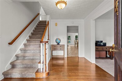 Staircase featuring ornamental molding, a textured ceiling, and wood finished floors