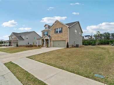 View of front of home featuring a garage, brick siding, concrete driveway, and a front lawn
