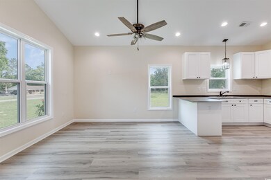 Kitchen featuring dark countertops, a sink, light wood-style floors, white cabinets, and recessed lighting