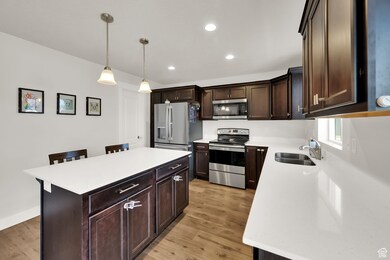 Kitchen featuring dark brown cabinetry, appliances with stainless steel finishes, a kitchen bar, pendant lighting, and recessed lighting