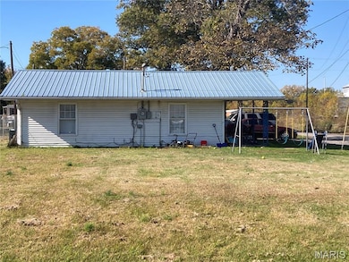Rear view of house with a lawn, a playground, a metal roof, and a carport