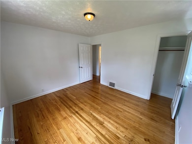 Unfurnished bedroom featuring a textured ceiling, light wood-type flooring, and a closet