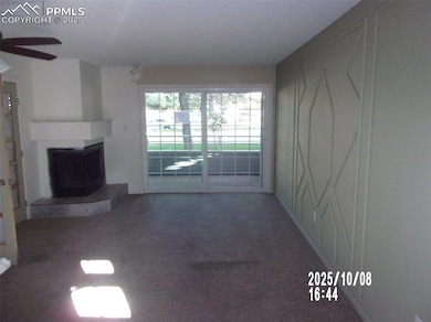 Unfurnished living room featuring carpet flooring, a fireplace with raised hearth, and ceiling fan