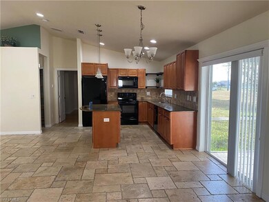 Kitchen with black appliances, a sink, lofted ceiling, backsplash, and dark countertops