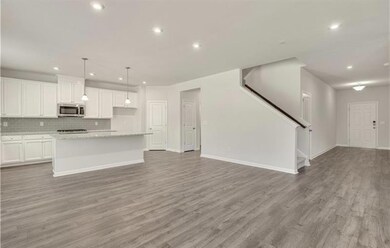 Kitchen with stainless steel microwave, open floor plan, light wood-type flooring, recessed lighting, and decorative backsplash