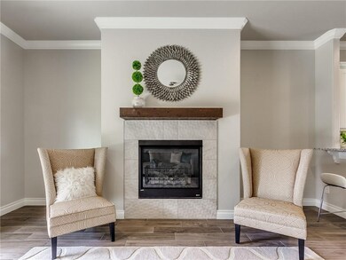 Gas fireplace with dimensional tile surround and rich wood mantle.