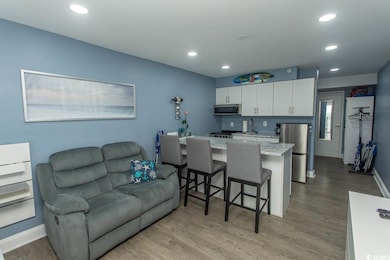 Kitchen with stainless steel appliances, open floor plan, white cabinets, a breakfast bar, and recessed lighting